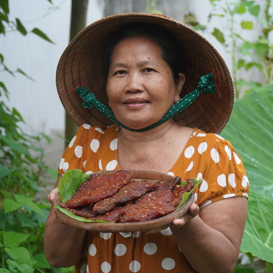 Cô Ba Miền Tây cầm mẹt khô bò một nắng thành phẩm tại vườn nhà